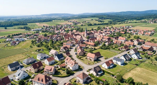 Photographie aérienne ou vue panoramique de la commune d'Innenheim en Alsace (Bas-Rhin), montrant un environnement résidentiel typique avec habitations, toitures, rues et espaces périurbains. L'image doit transmettre un sentiment de proximité locale et représenter une petite commune alsacienne où intervient l'entreprise de rénovation, visuellement distincte des vues panoramiques de Fegersheim et Mutzig déjà utilisées. La perspective aérienne doit clairement identifier Innenheim comme une commune alsacienne avec ses caractéristiques architecturales propres.